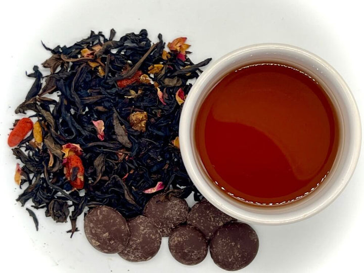Tea leaves, a cup of tea, and chocolate pieces on a white background
