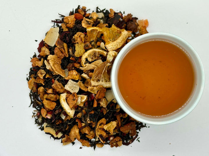 Tea leaves and a cup of brewed tea on a white background
