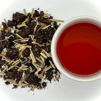 Tea leaves and a cup of brewed tea on a white background