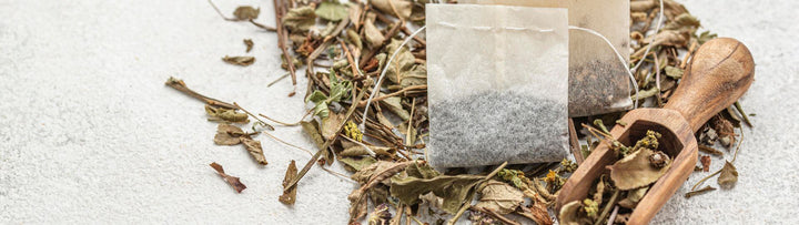 Tea leaves with a tea bag and wooden scoop on a light background