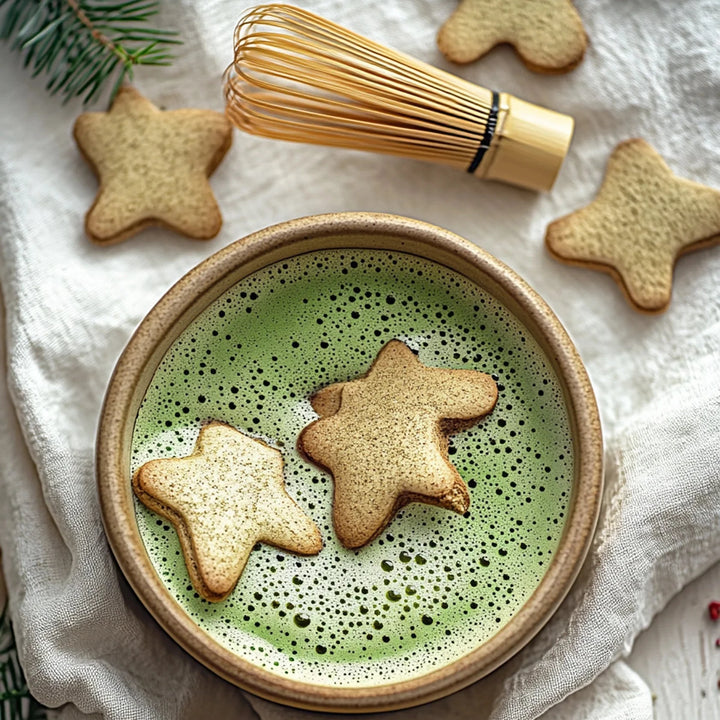 Matcha green tea in a wooden bowl with star-shaped cookies on a white cloth background.